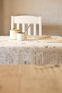 two coffee cups on a table with a white chair at Pumpkin Tree Guesthouse in Middelburg