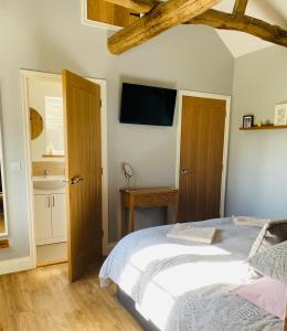 a bedroom with a bed and a tv on the wall at Rivers Rest in Norwich