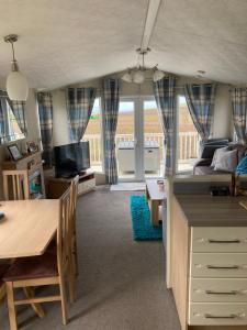 a kitchen and living room with a table and a couch at Luxury caravan at Turnberry - short walk to beach in Girvan