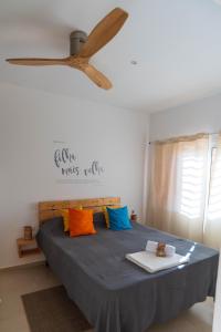 a bedroom with a bed with colorful pillows and a ceiling fan at Amwilla Guesthouse Apartamento Elsa in Mindelo