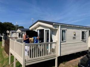 a woman standing on the porch of a mobile home at Luxury caravan at Turnberry - short walk to beach in Girvan