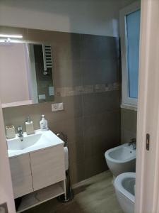 a bathroom with a sink and a toilet and a mirror at Riviera Albachiara Anzio B&B in Anzio