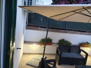 a patio with a chair and an umbrella on a balcony at Riviera Albachiara Anzio B&B in Anzio
