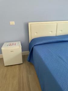 a bed with a blue blanket and a box next to it at Riviera Albachiara Anzio B&B in Anzio