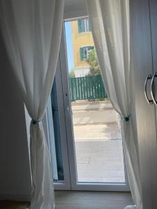 a sliding glass door with white curtains in a room at Riviera Albachiara Anzio B&B in Anzio