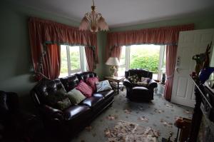 a living room with a leather couch and two chairs at Haywoods B&B in Donegal
