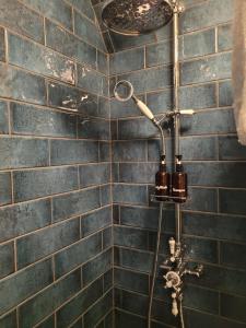 een douche in een badkamer met blauwe tegels bij Afallon Townhouse Salop Room in Dolgellau