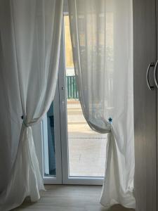 an open door with white curtains in a room at Riviera Albachiara Anzio B&B in Anzio