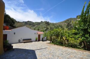 a white building with a bench in front of a mountain at Casa Rural Casa Manuel in Moya