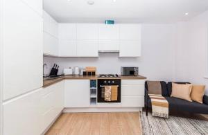 uma cozinha com armários brancos e um sofá em Elegant Central, Private Parking, Leisure, Contractor em Buckinghamshire
