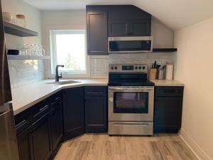 uma cozinha com armários pretos, um fogão e um lavatório em County Cove - Bloomfield Suite em Wellington