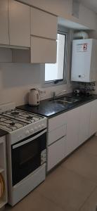a kitchen with a stove and a sink and a microwave at Departamento Solares - San Martin in Bahía Blanca