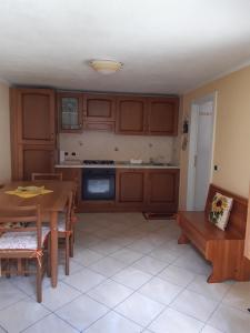 una cocina con armarios de madera, mesa y sillas en Le tue vacanze a Varzo, appartamento il girasole. en Varzo