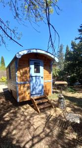 uma cabana de madeira com uma porta e uma mesa de piquenique em La roulotte à Juju em Le Bosc