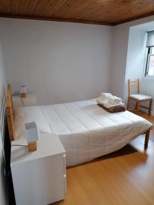 a white bedroom with a large bed and a chair at Rosa do Canto in Monte