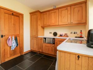 a kitchen with wooden cabinets and a counter top at Pound Cottage in Great Torrington