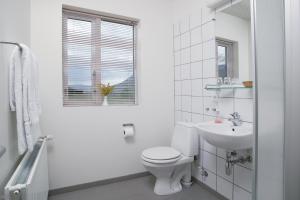 a white bathroom with a toilet and a sink at Hótel Tjarnir in Ljósavatn