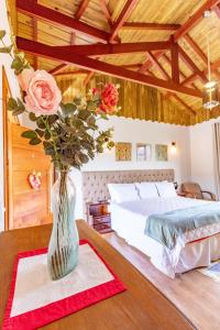 a vase with roses on a table in a bedroom at Pousada Posto Monte Verde in Monte Verde