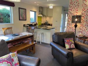 eine Küche und ein Wohnzimmer mit einem Sofa und einem Tisch in der Unterkunft Cottage on Kent in Arrowtown