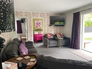 ein Wohnzimmer mit einem Sofa und einem TV an der Wand in der Unterkunft Cottage on Kent in Arrowtown