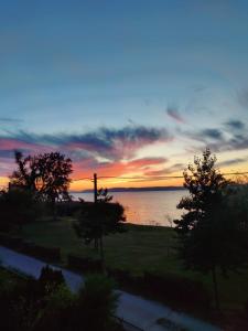 una puesta de sol sobre un cuerpo de agua con árboles en Traumlage direkt am See, en Balatonszemes