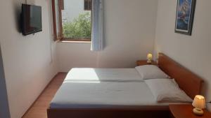 a small bedroom with a bed and a window at Apartments Rosa in Mali Lošinj
