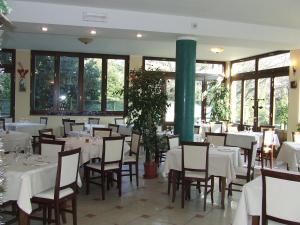 restauracja z białymi stołami, krzesłami i oknami w obiekcie Mediterraneo w mieście Pianoro