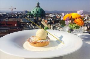 a dessert on a plate with a view of a city at DO&CO Hotel Vienna in Vienna