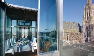 a table and chairs on a balcony with a view of a city at DO&CO Hotel Vienna in Vienna