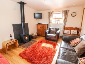 uma sala de estar com um sofá e um fogão a lenha em Orchard Cottage em Ashbourne