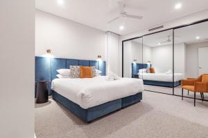 彭里斯Astina Suites, Penrith的带一张大床和一把椅子的卧室