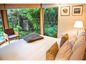 a bedroom with a white bed and a large window at River Birches in Turangi