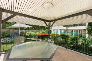 eine überdachte Terrasse mit einem Tisch und einem Sonnenschirm in der Unterkunft Reef Gateway Apartments in Cairns