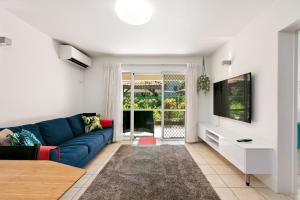 sala de estar con sofá azul y TV en Reef Gateway Apartments, en Cairns
