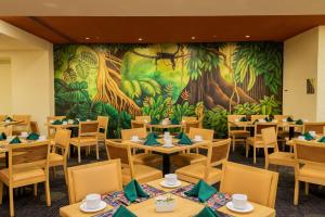 a restaurant with tables and chairs in front of a mural at Camino Real Polanco Mexico in Mexico City