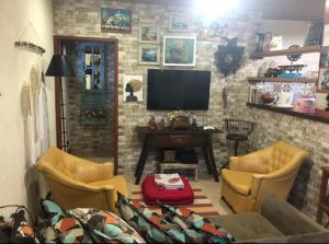 a living room with yellow chairs and a flat screen tv at Casa de campo com piscina em Paty do alferes in Paty do Alferes