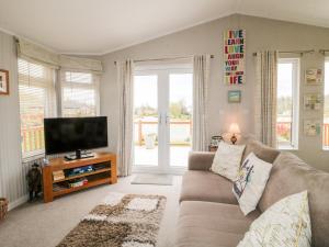 een woonkamer met een bank en een flatscreen-tv bij Lake View Lodge in Grantham