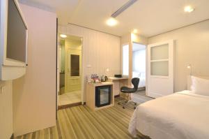 台北市にあるYomi Hotel - ShuangLian MRTのベッド、デスク、椅子が備わるホテルルームです。