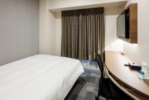 岡山市にあるスマイルホテル　岡山のベッド、デスク、テレビが備わるホテルルームです。