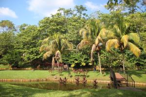 un parque con palmeras, un banco y un estanque en Villa Amanda Resort, en Mazatenango