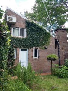 an ivy covered brick house with a white door at Las Calandrias in Funes