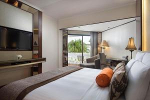 a hotel room with a large bed with a television at Anantara Riverside Bangkok Resort in Bangkok