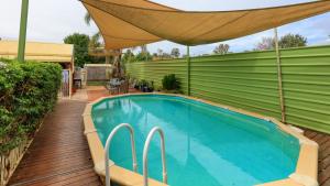 a swimming pool with an umbrella on a deck at Barham Riverland Motel in Barham