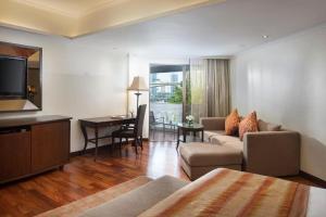 a living room with a couch and a table and a television at Anantara Riverside Bangkok Resort in Bangkok