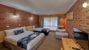 a hotel room with two beds and a brick wall at Barham Riverland Motel in Barham