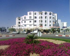 a large white building with pink flowers in front of it at Excellente Appartement Entre Monastir Et Sousse in Sahline