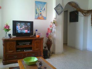 a living room with a television on a wooden entertainment center at Excellente Appartement Entre Monastir Et Sousse in Sahline