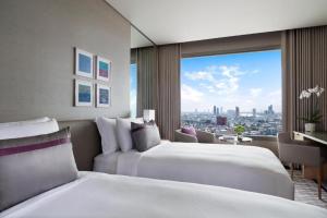 
a hotel room with two beds and two windows at Avani Plus Riverside Bangkok Hotel -SHA Plus Certified in Bangkok
