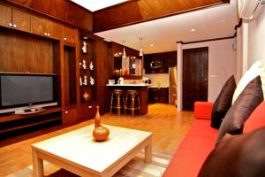 a living room with a red couch and a tv at Rayaburi Hotel, Patong in Patong Beach