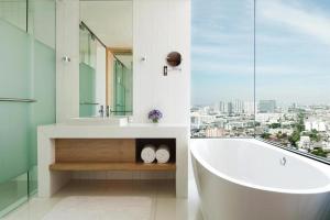 a white bathroom with a tub and a window at Avani Plus Riverside Bangkok Hotel in Bangkok